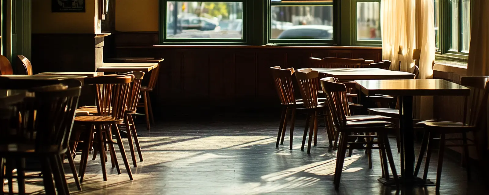 An empty dining room in morning light, chairs at the tables.